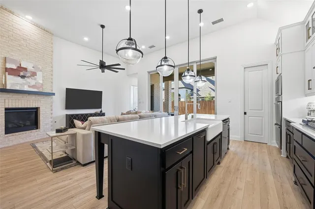 a kitchen with a stove oven a sink dishwasher a dining table and chairs with wooden floor