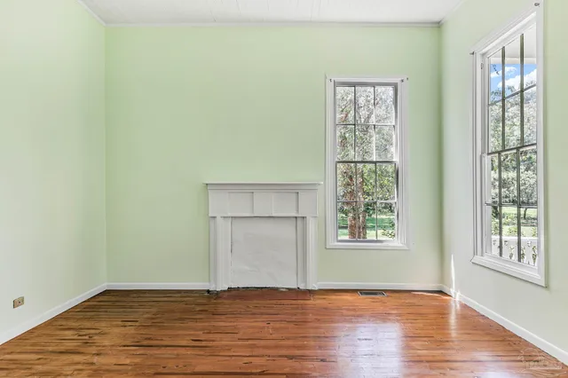 an empty room with wooden floor cabinet and windows