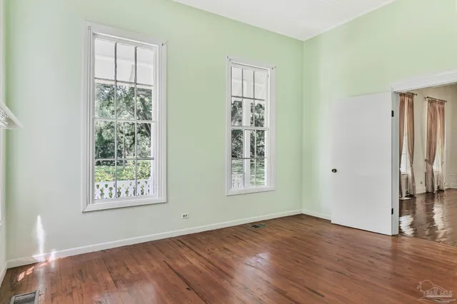 a view of empty room with wooden floor and ceiling fan