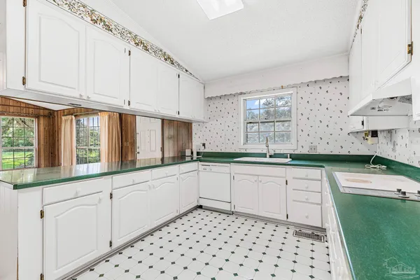 a white kitchen with granite countertop white cabinets and stainless steel appliances