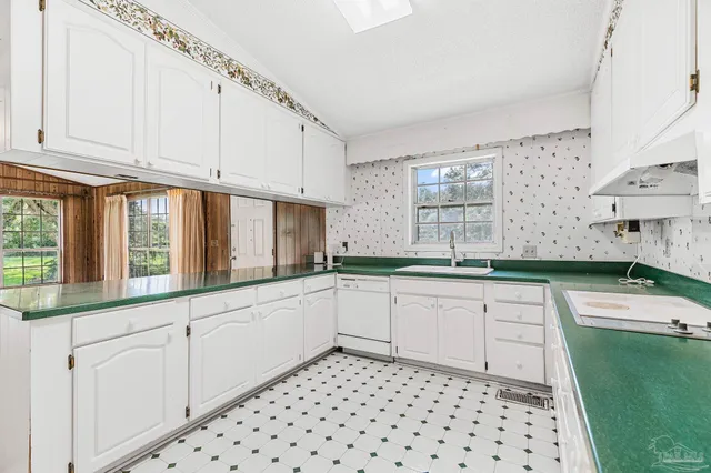 a white kitchen with granite countertop white cabinets and stainless steel appliances