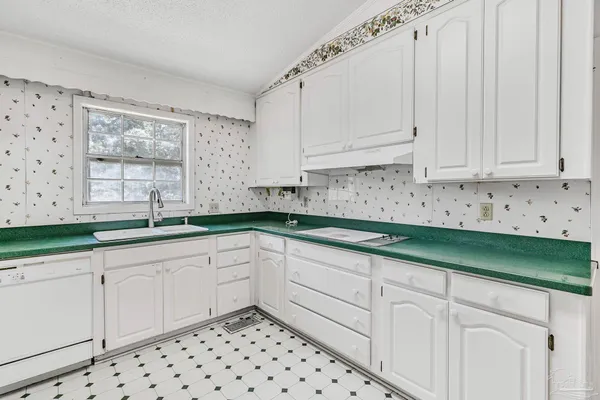 a kitchen with granite countertop white cabinets and two windows