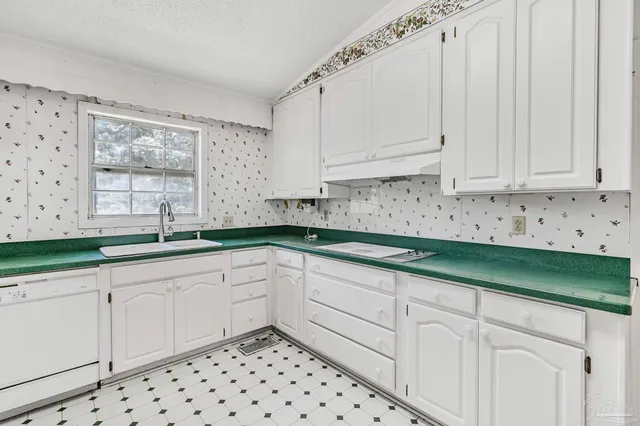 a kitchen with granite countertop white cabinets and two windows