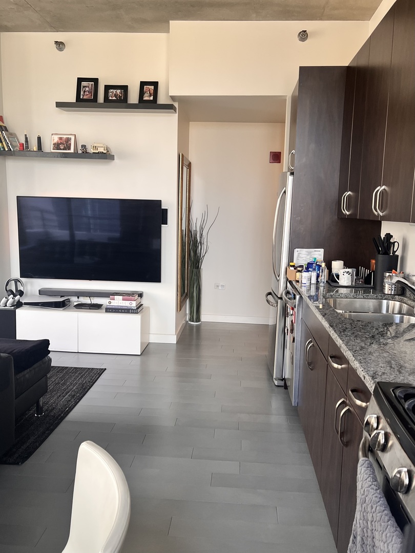 235 West Van Buren Street, Unit 2415 Chicago, IL 60607 - Photo 4 of 19 a kitchen with stainless steel appliances kitchen island granite countertop a stove a sink and a microwave