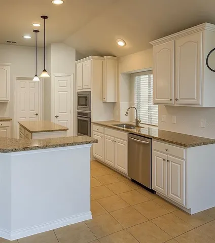 a kitchen with stainless steel appliances granite countertop a sink a stove and a refrigerator