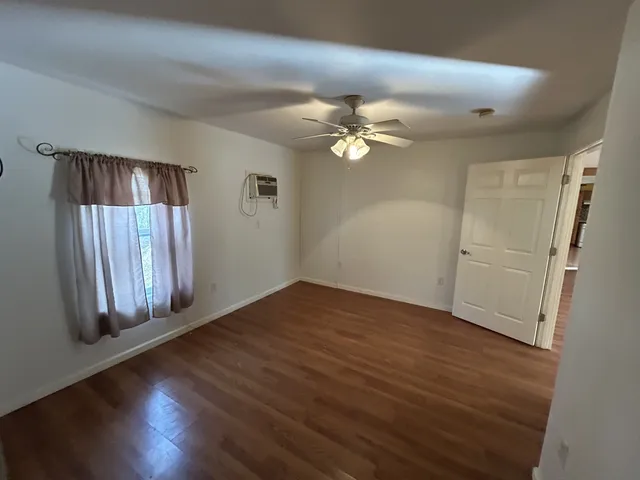 an empty room with wooden floor and window
