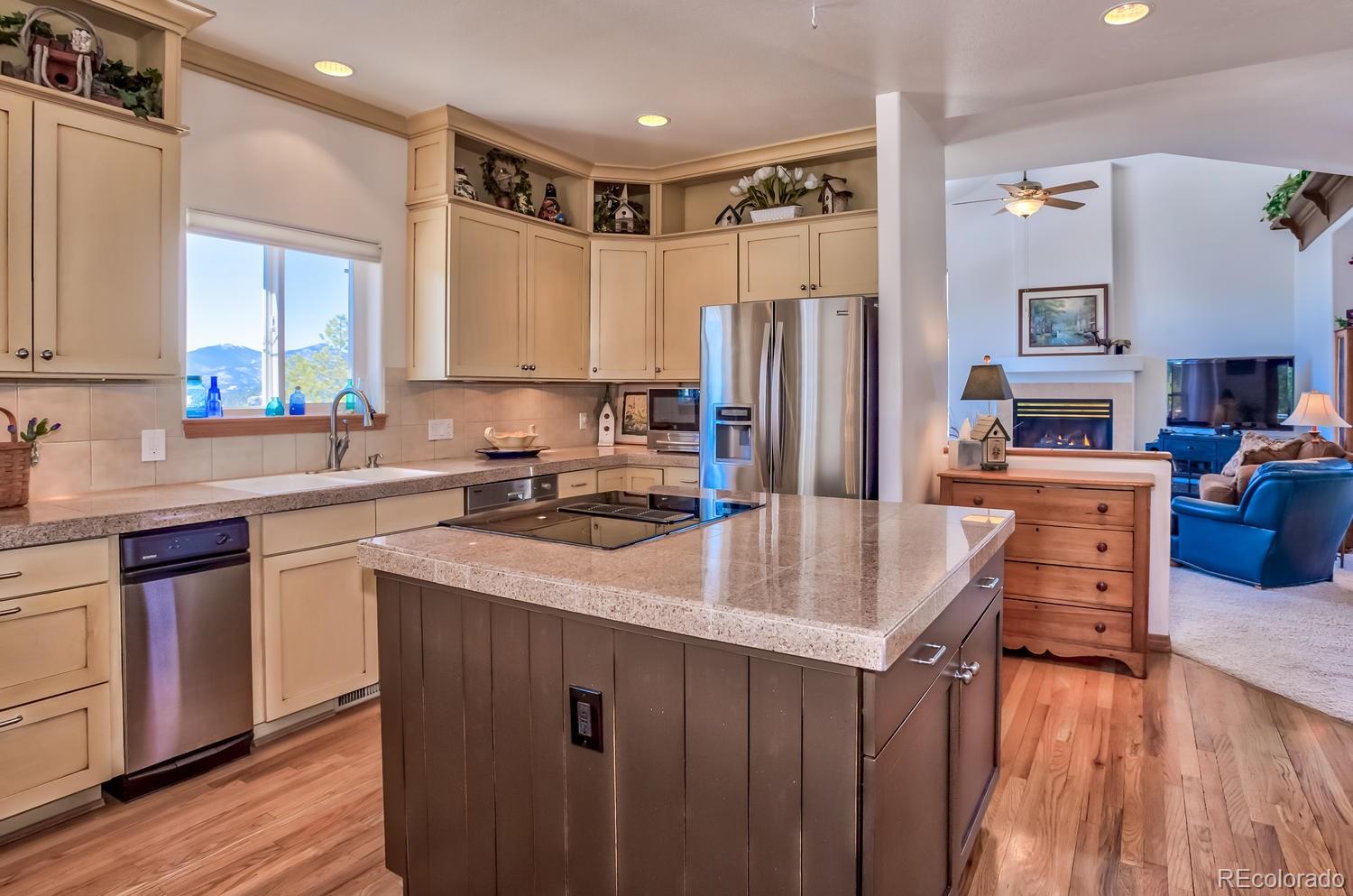 29323 Gray Hawk Drive Evergreen, CO 80439 - Photo 6 of 31 a kitchen with stainless steel appliances granite countertop a refrigerator a sink dishwasher a stove and a dining table with wooden floor