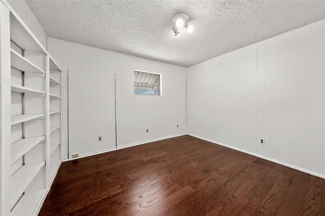 an empty room with wooden floor and ceiling fan