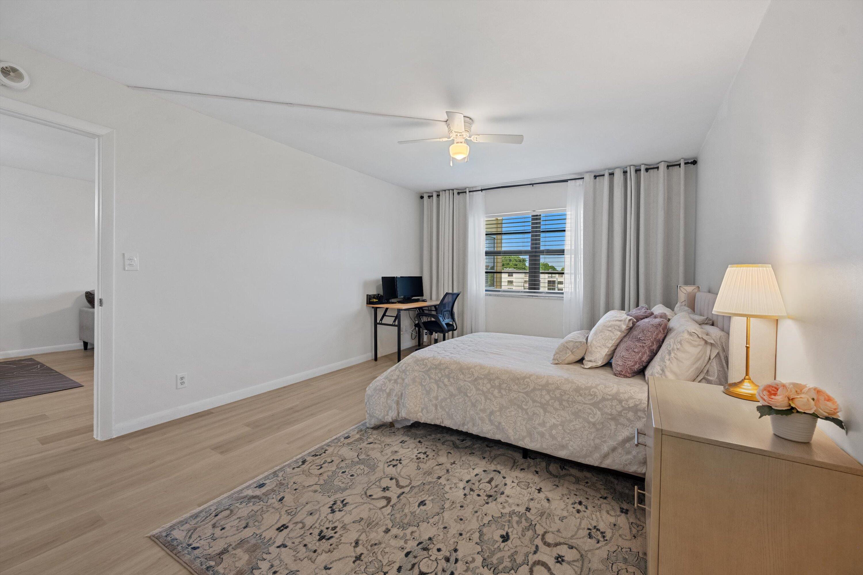 9273 Southwest 8th Street, Unit 416 Boca Raton, FL 33428 - Photo 11 of 19 a bedroom with a bed and a dresser with wooden floor