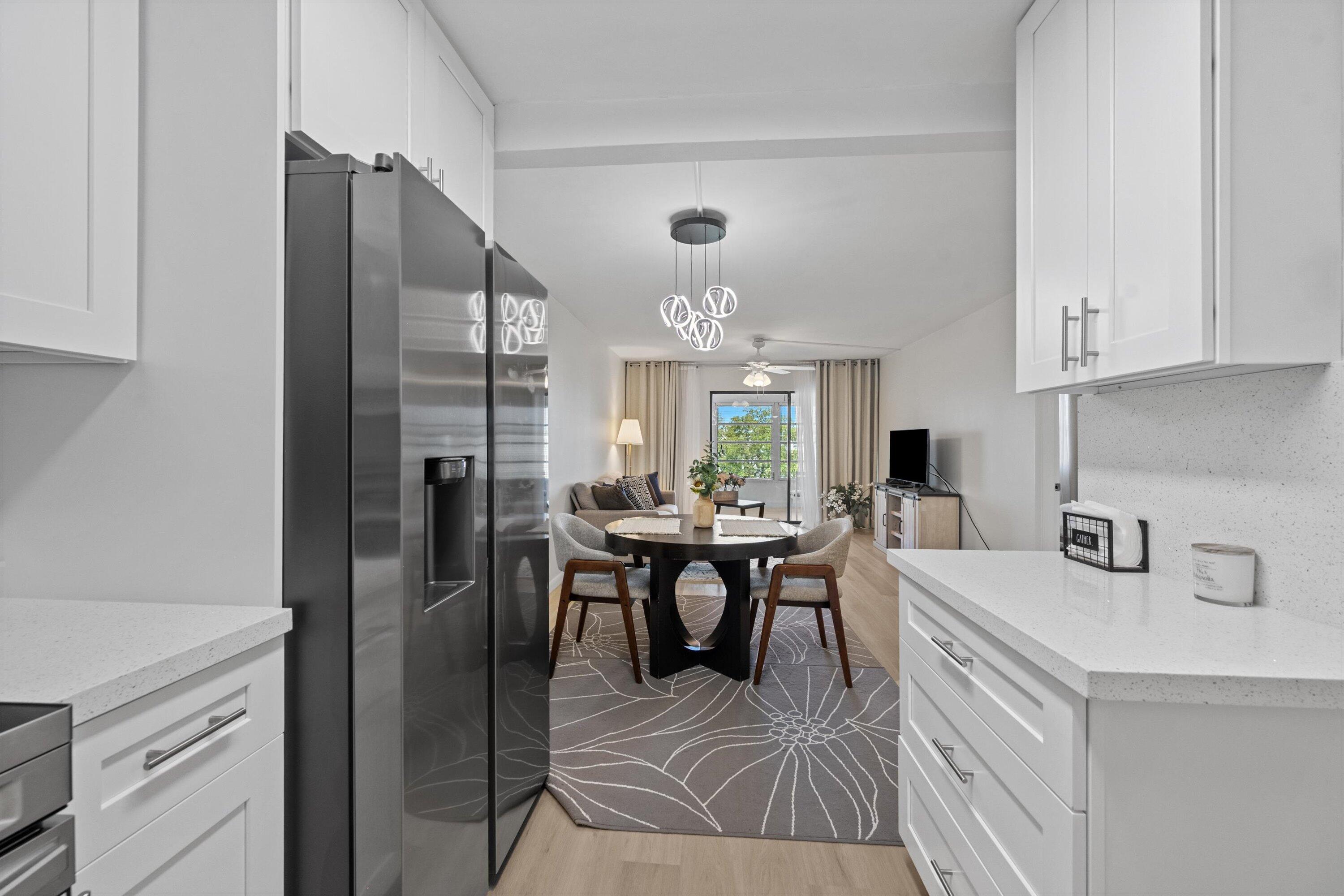 9273 Southwest 8th Street, Unit 416 Boca Raton, FL 33428 - Photo 2 of 19 a kitchen with stainless steel appliances granite countertop a refrigerator a sink a stove and white cabinets