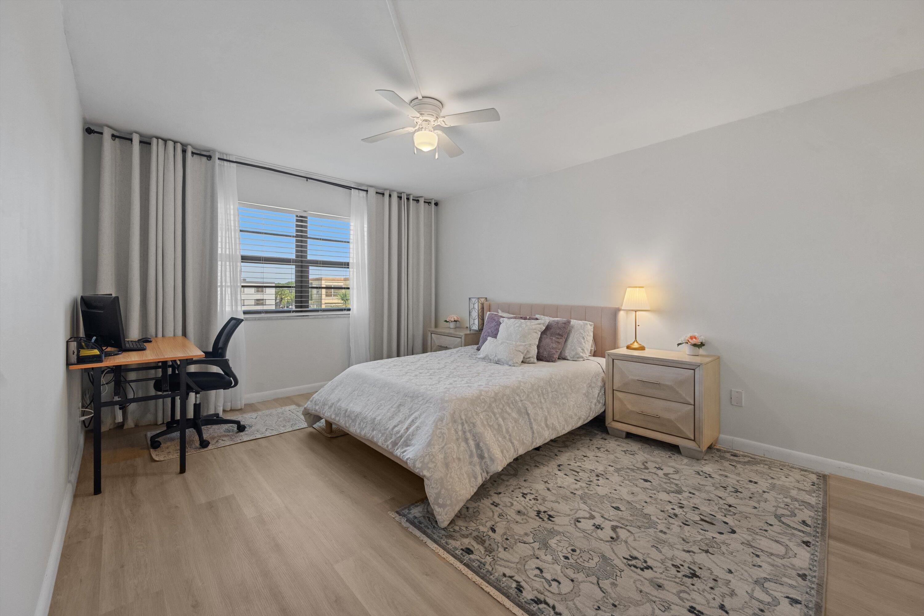 9273 Southwest 8th Street, Unit 416 Boca Raton, FL 33428 - Photo 10 of 19 a bedroom with a bed table chair and a window