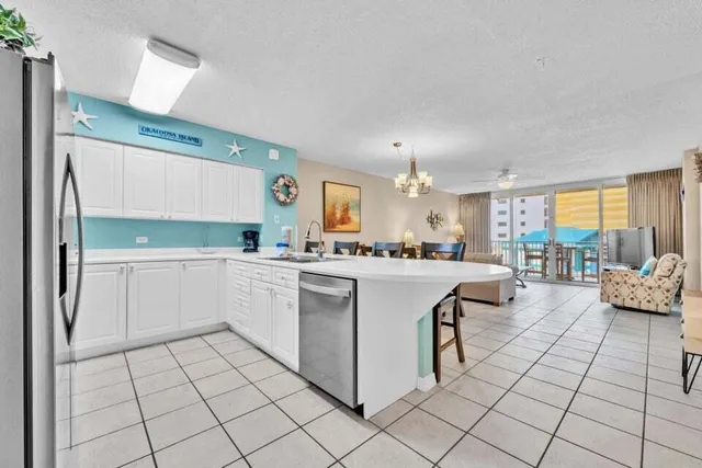 a large white kitchen with a stove a sink dishwasher and a dining table with kitchen view