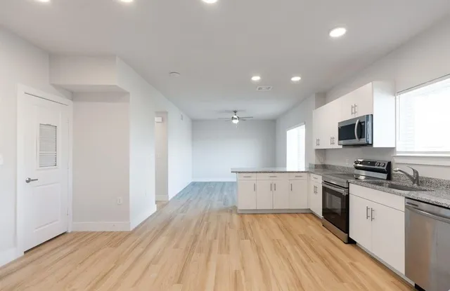 a kitchen with granite countertop a stove top oven a sink dishwasher and a refrigerator with wooden floor