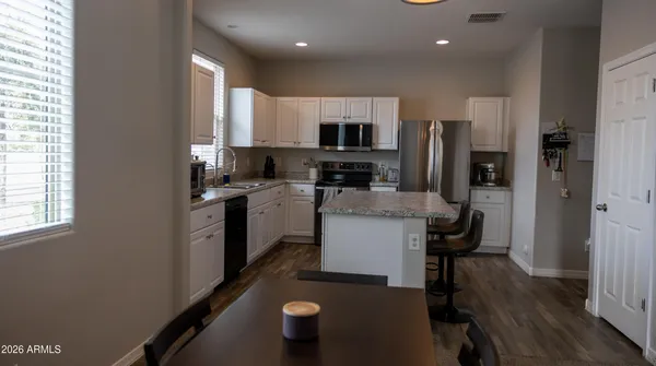 a kitchen with kitchen island granite countertop wooden cabinets a sink dishwasher a stove and a refrigerator