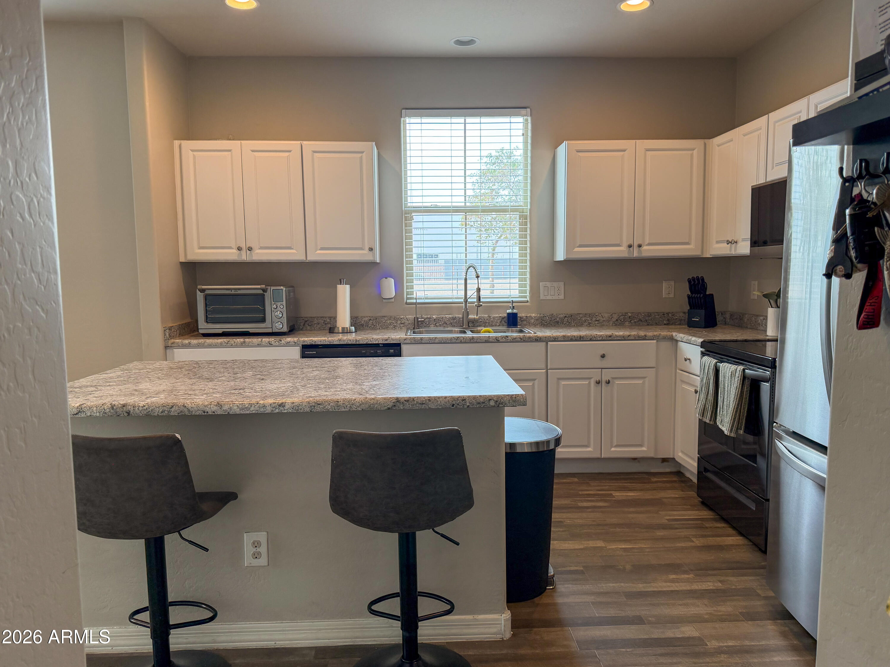 5480 Fulton Street Phoenix, AZ 85043 - Photo 15 of 63 a kitchen with stainless steel appliances granite countertop a stove top oven a refrigerator a sink and white cabinets with wooden floor