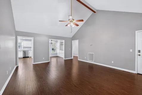 a view of an empty room with a window and wooden floor