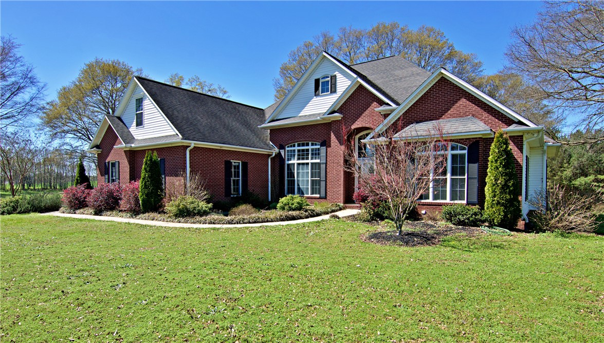 7893 Athens Road Carnesville, GA 30521 - Photo 3 of 50 This charming residence features classic brick and siding, nestled among mature trees and lush greenery.