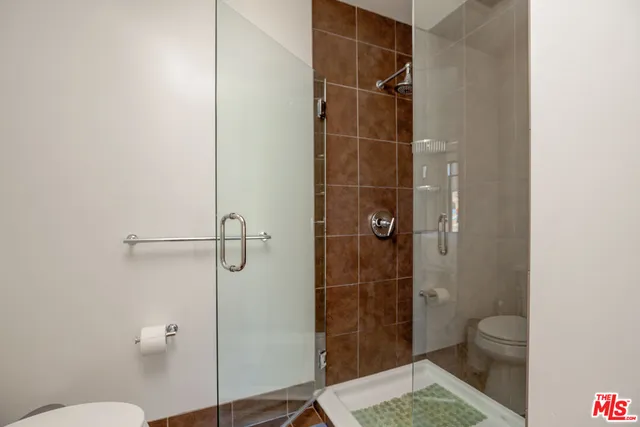 a bathroom with a glass door shower and a toilet