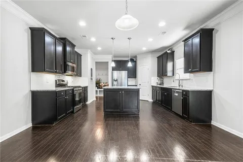 a large kitchen with stainless steel appliances kitchen island granite countertop a large cabinets a sink and a stove