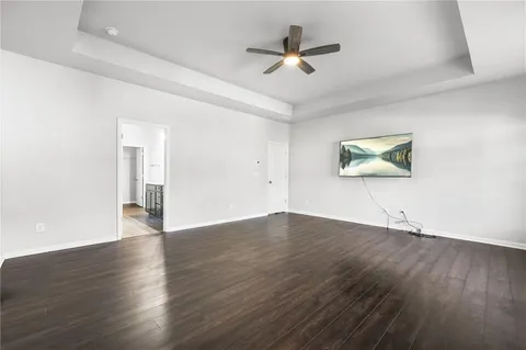 a view of an empty room with wooden floor and a ceiling fan