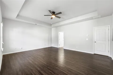 an empty room with wooden floor a ceiling fan and windows