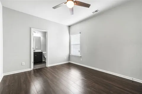 a view of an empty room with wooden floor and a ceiling fan