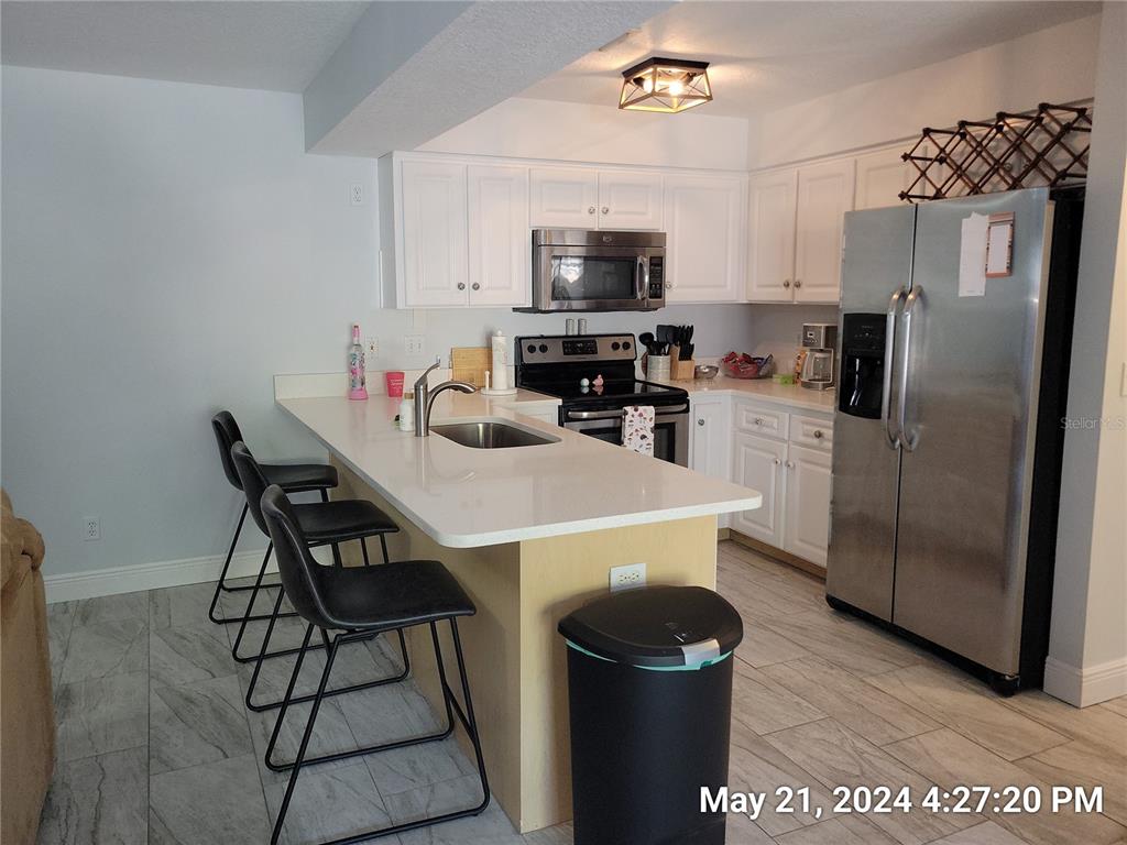 1013 Apollo Beach Boulevard, Unit 101 Apollo Beach, FL 33572 - Photo 3 of 19 a kitchen with stainless steel appliances a refrigerator a stove a sink a dining table and chairs
