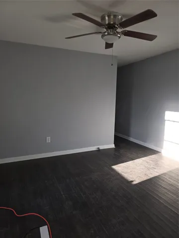 an empty room with wooden floor fan and window