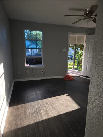 a view of an empty room with wooden floor and a window