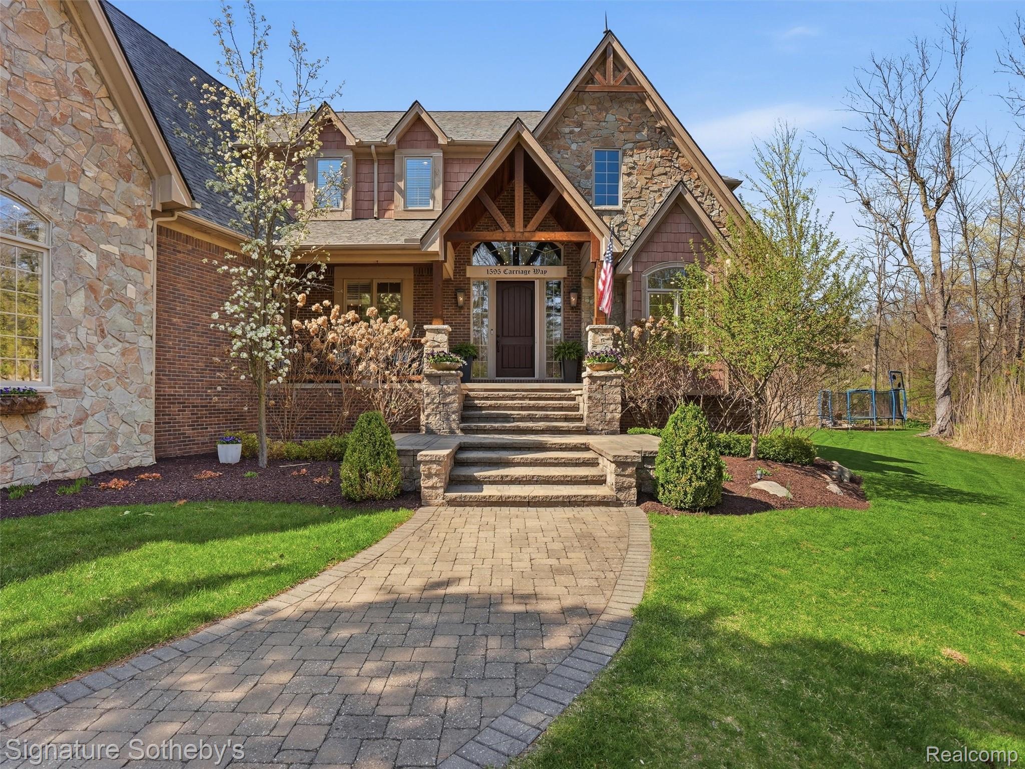 1595 Carriage Way Rochester, MI 48307 - Photo 5 of 78 Craftsman-style house featuring stone siding, a front yard, a porch, and a trampoline