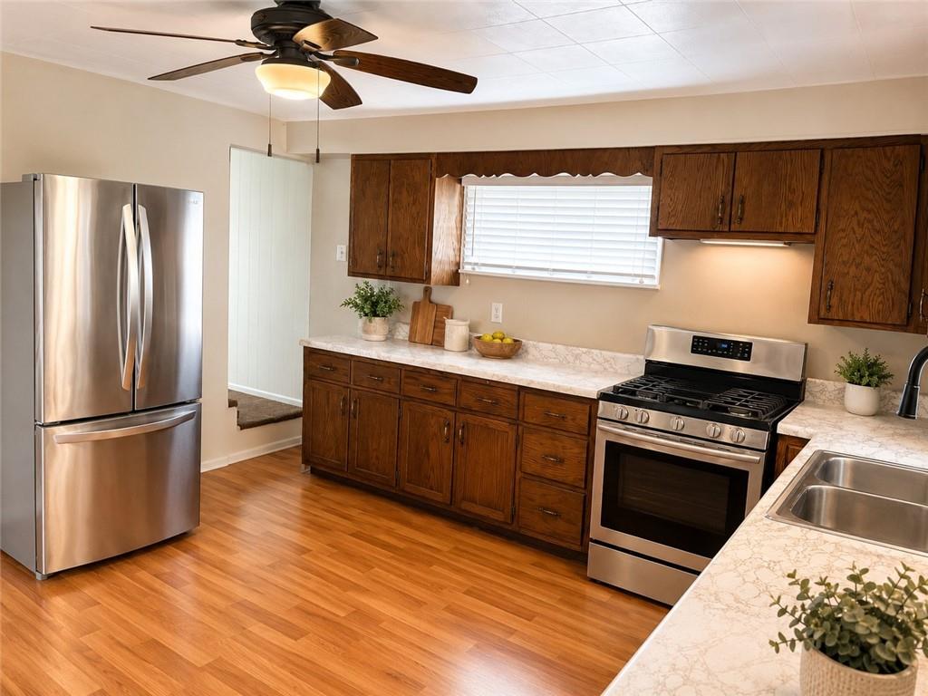 9155 Maple Street Pittsburgh, PA 15239 - Photo 6 of 16 a kitchen with stainless steel appliances granite countertop a refrigerator a sink dishwasher a stove and white countertops with wooden floor
