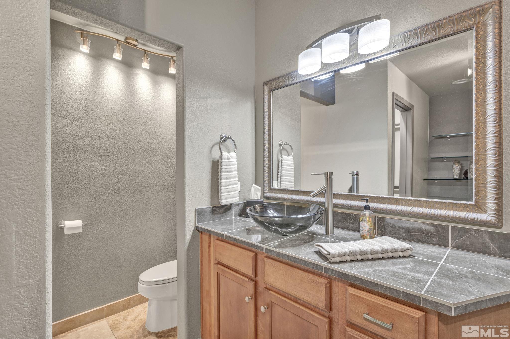 17000 Wedge Parkway, Unit 3422 Reno, NV 89511 - Photo 17 of 39 a bathroom with a granite countertop sink a toilet and a mirror