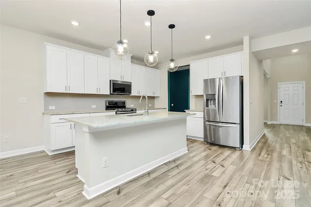 a kitchen with stainless steel appliances white cabinets a sink a refrigerator and a stove