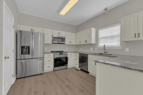 a kitchen with granite countertop white cabinets and stainless steel appliances