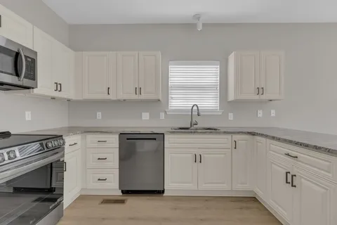 a kitchen with granite countertop white cabinets and stainless steel appliances
