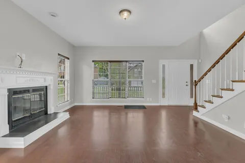 a view of an empty room with wooden floor fireplace and a window