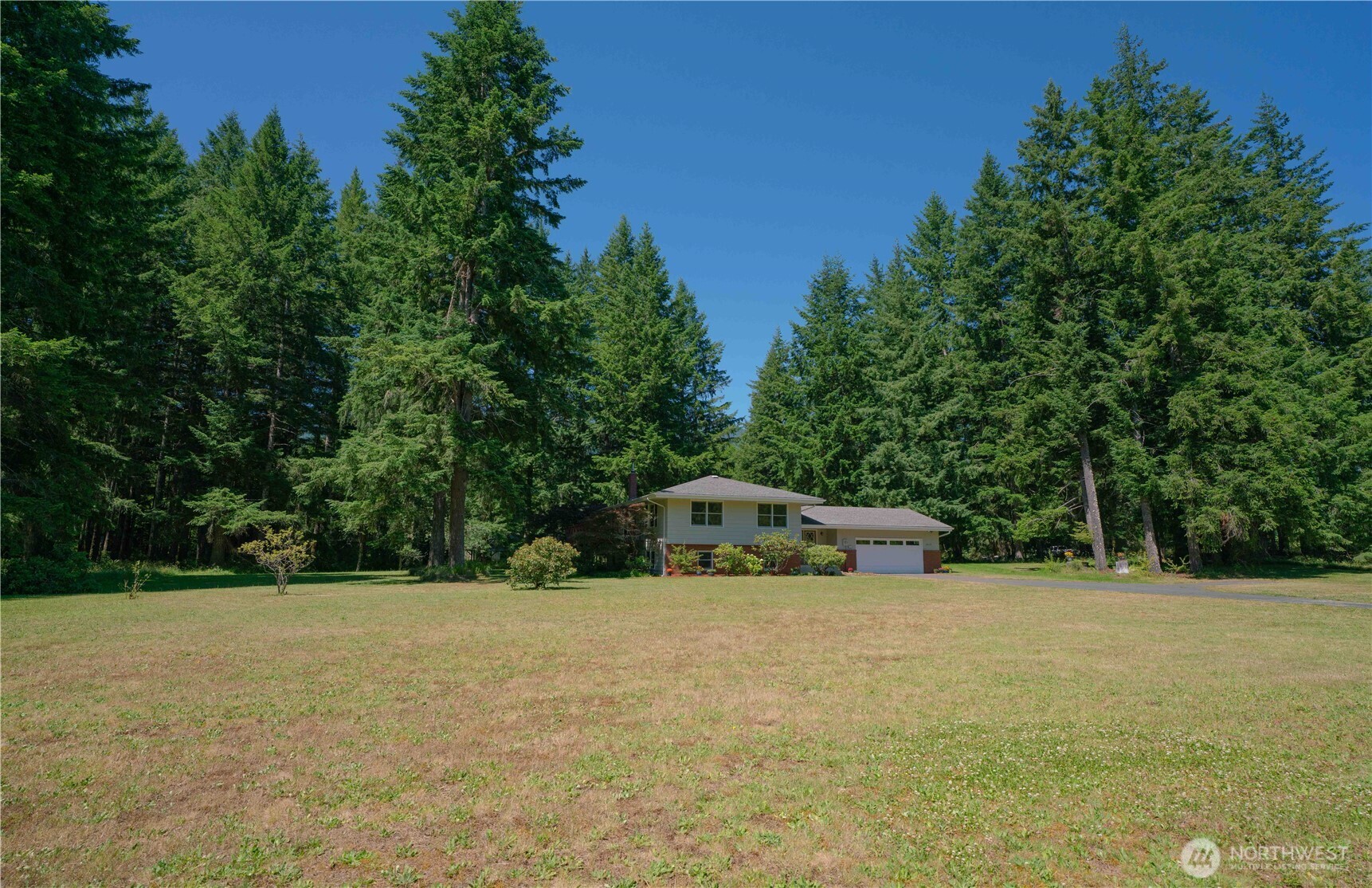 293154 Highway 101 Quilcene, WA 98376 - Photo 31 of 40 a white house with a yard and trees in the background