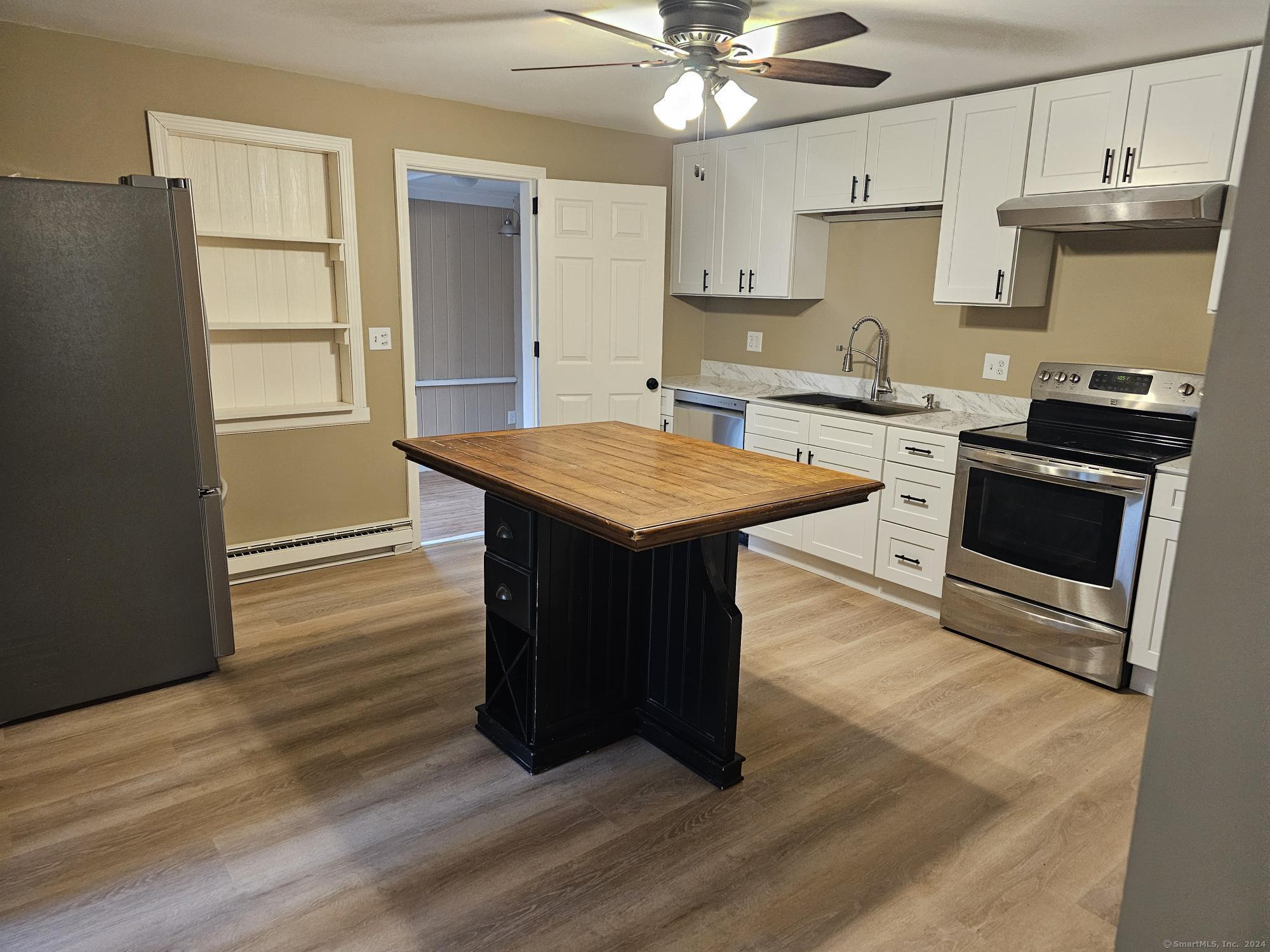 a kitchen with stainless steel appliances granite countertop a stove a sink dishwasher and a refrigerator with wooden floor