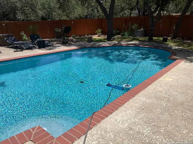 a view of a backyard with chairs and potted plants
