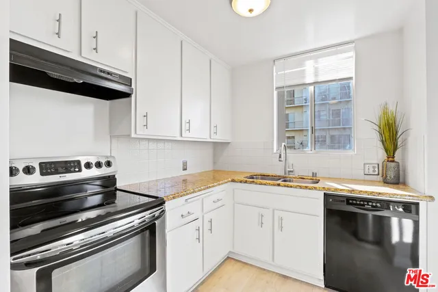 a kitchen with stainless steel appliances a sink dishwasher a stove and white cabinets