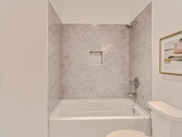 a white bath tub sitting next to a white toilet and vanity