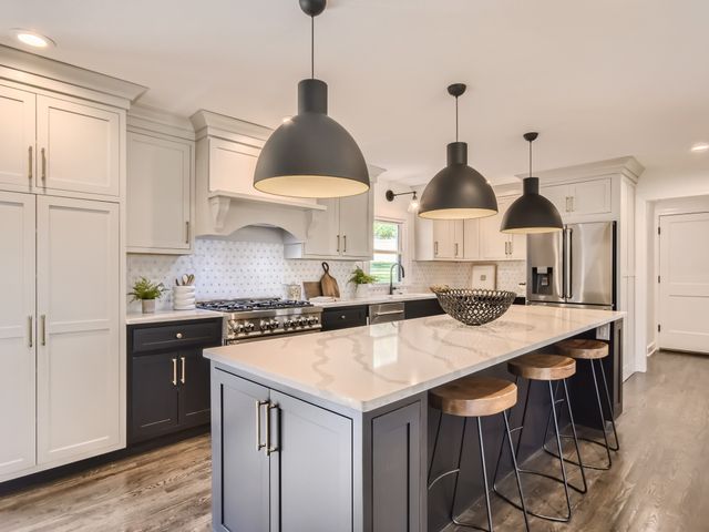 a kitchen with stainless steel appliances a stove a sink a center island and cabinets