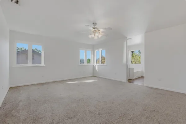 an empty room with windows and chandelier fan