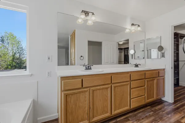 a spacious bathroom with a double vanity sink a large mirror and shower