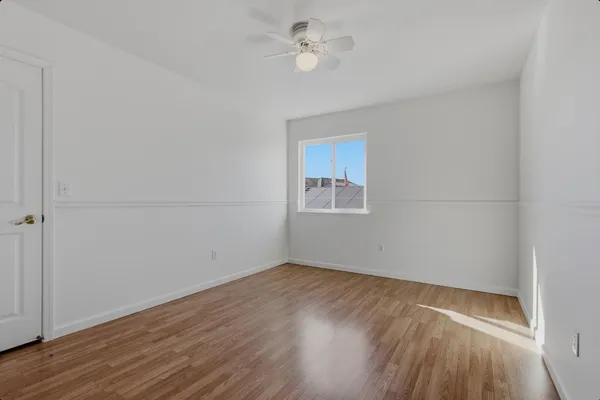 an empty room with a window and ceiling fan