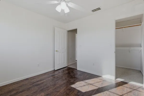 an empty room with wooden floor and chandelier fan