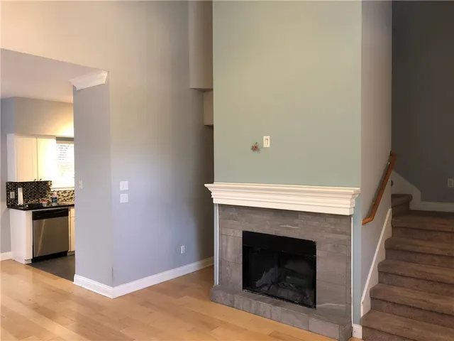 a view of an empty room with wooden floor and a fireplace