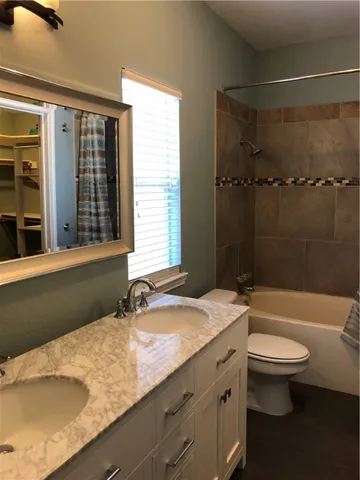 a bathroom with a granite countertop sink toilet a mirror and bathtub