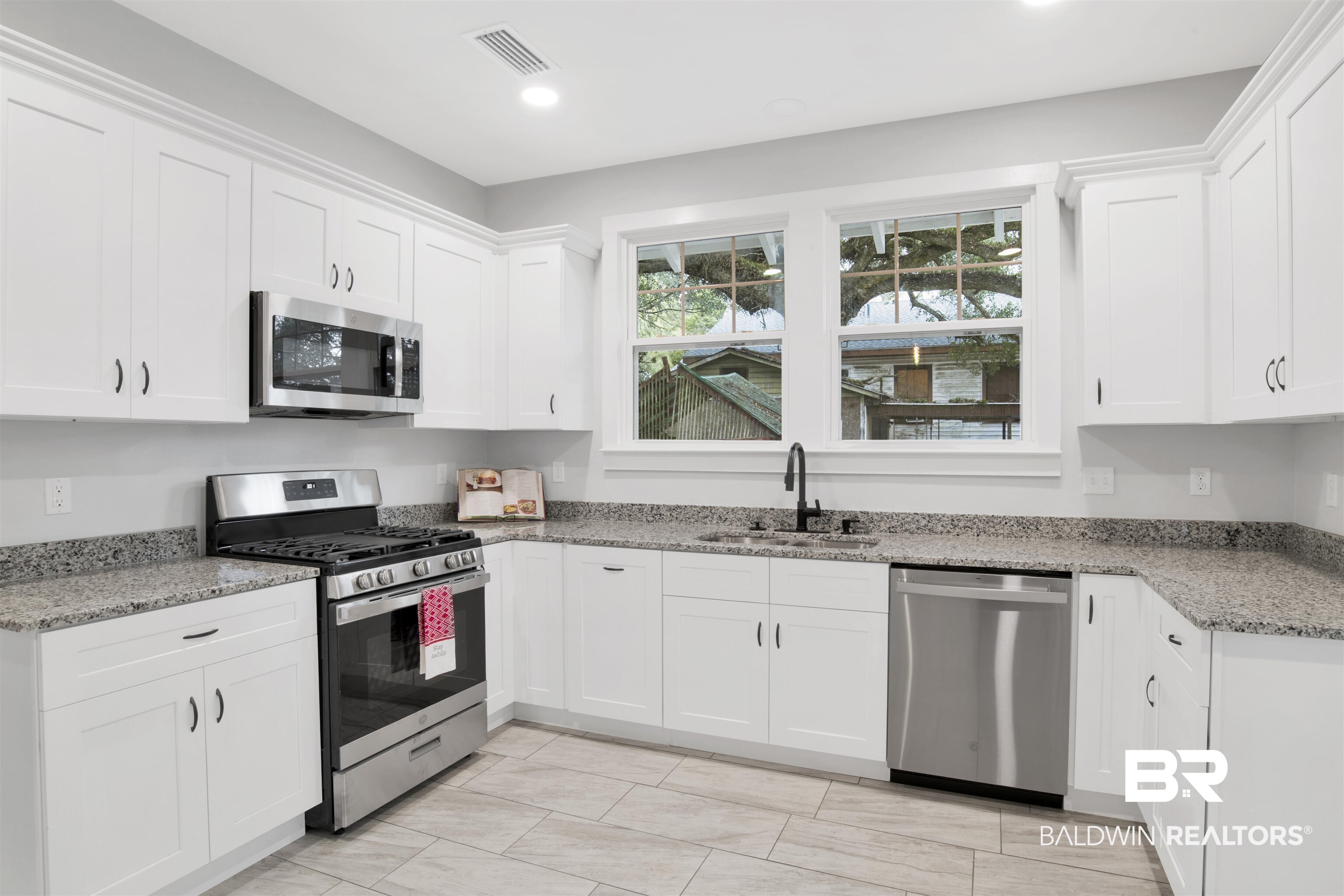 302 1st Street Mobile, AL 36611 - Photo 12 of 28 Kitchen with stainless steel appliances, white cabinetry, sink, and light stone counters