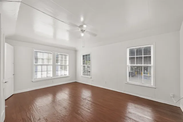a view of an empty room with a window and wooden floor